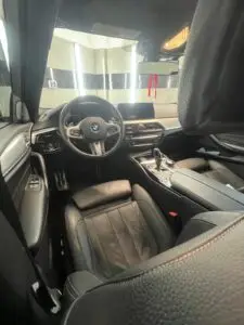 Realizacja: umyte BMW w garażu, widoczne wnętrze auta zza fotela kierowcy