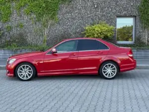 Czerwony Mercedes przygotowany do sprzedaży w myjni ręcznej - widok na auto z profilu