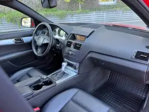 Czerwony Mercedes przygotowany do sprzedaży w myjni ręcznej - widok kokpit auta zza siedzenia pasażera