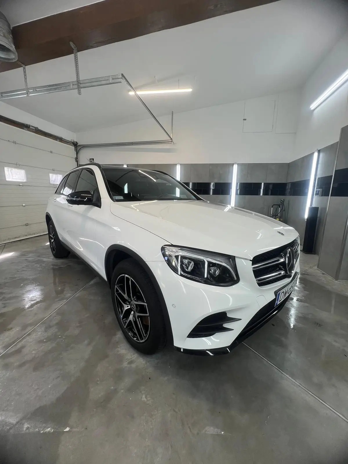 Biały samochód umyty z zewnątrz w myjni ręcznej - widok na auto z ukosa