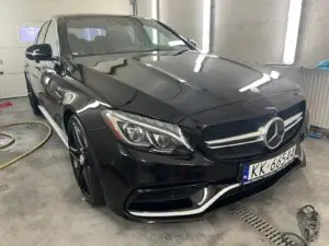 Czarny Mercedes wyczyszczony z zewnątrz w myjni ręcznej - widok z ukosa na przód auta